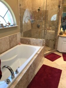 A bathroom remodeled with new tile walls, tile floor, shower glass, and paint.