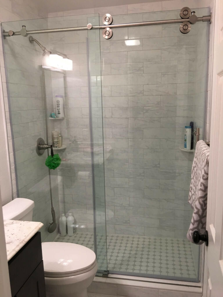 Bathroom remodeled with new wall and floor tile, shower tile, granite counters, vanity, paint, lights, mirror, and toilet.