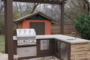 Outdoor kitchen remodeled with new concrete, new counters, new cabinets, new sink, new stone facing, and new pergola.