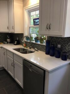 Kitchen remodeled with new floor tile, backsplash tile, vent hood, cabinets, paint, floor tile, and appliances.
