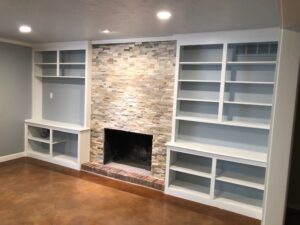 This remodeled living room includes new texture with a painted ceiling, walls, and bookshelves, a new stone exterior on the fireplace, and new LED lighting.