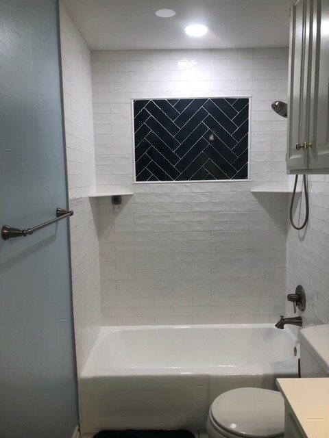 New bathroom with painted walls, resurfaced tub, LED lighting, and custom tile design in shower.