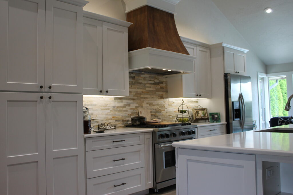 A kitchen remodeled with new grand island, cabinets, quartz counters, engineered wood floors, and painted walls.