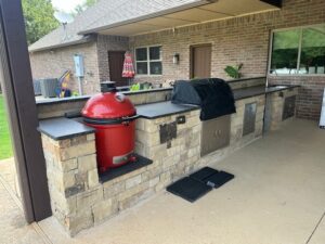 New custom-built outdoor kitchen with stone countertops, grill, and ample counter space.