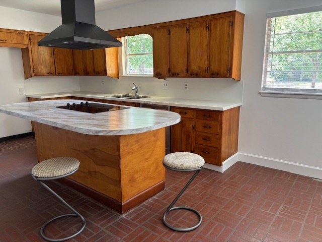 Updated 1970’s kitchen with wood cabinets, new laminate island countertop, modern vent hood, and barstool seating