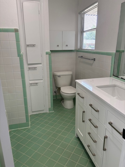 Bathroom with green and white tile, white vanity with chrome hardware, and updated fixtures