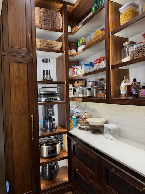 Custom food pantry in Edmond featuring handcrafted stained cabinets, LED lighting, custom backsplash, and new countertops.